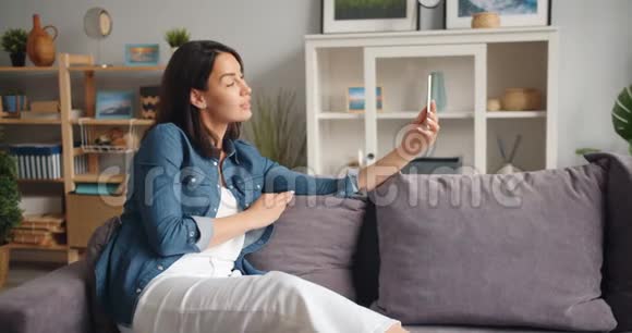 漂亮女孩在家里用智能手机在线视频通话的慢动作视频的预览图