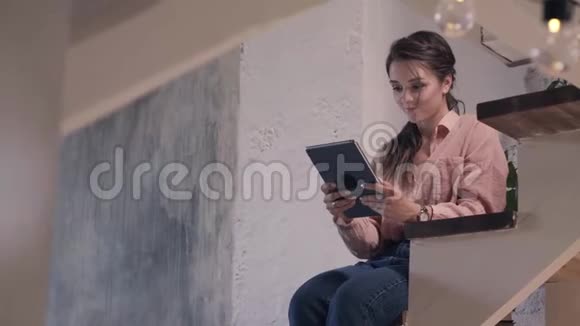 年轻女子用数码平板电脑休息库存录像穿着粉红色衬衫的美丽微笑女人的特写视频的预览图