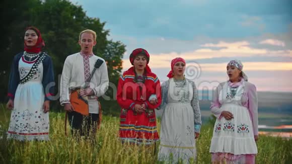 人们穿着传统的民间服装在田野上散步唱着一首歌日落视频的预览图