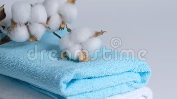 白色和蓝色干净的毛巾和白色背景上的棉树枝特写慢镜头视频的预览图