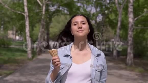 一个漂亮的年轻女孩走在街上在炎热的夏天吃冰淇淋视频的预览图