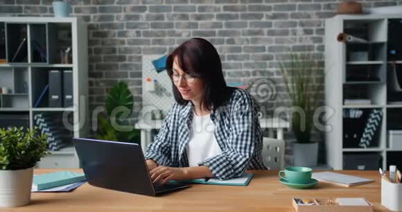 一个人在办公室办公桌上拿着笔记本电脑的漂亮女人动作缓慢视频的预览图