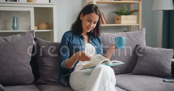 可爱的学生看书在沙发上喝咖啡放松视频的预览图