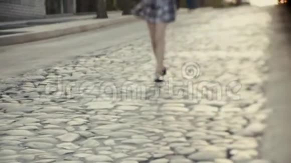 一个穿凉鞋的小女孩的腿和一条沿着路跑的短格子裙子视频的预览图