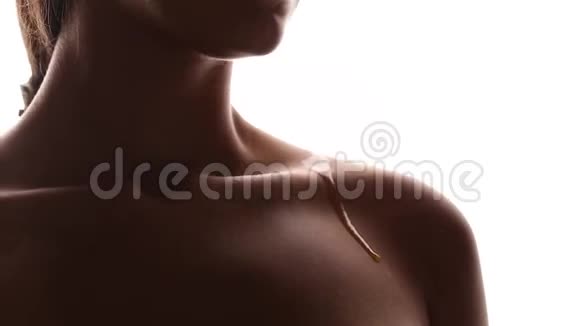 白色背景上的女孩皮肤干净一滴化妆品油流下身体肩膀收拢视频的预览图