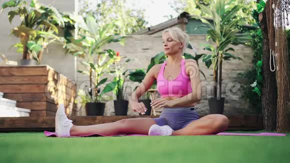 年轻女性在家草坪上做伸展运动慢动作健康生活方式的概念视频的预览图