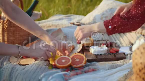 两个女人在野餐毯子上有水果和甜点视频的预览图