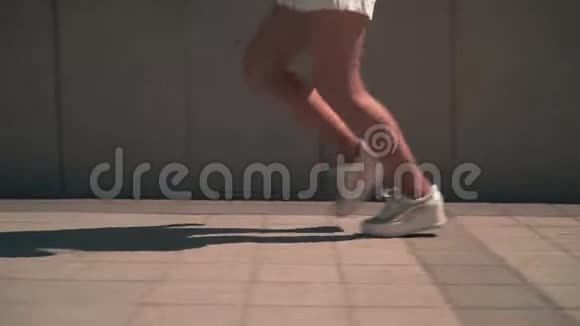 女性腿的特写一个穿着白色运动鞋腿晒黑的女孩沿着人行道跑视频的预览图