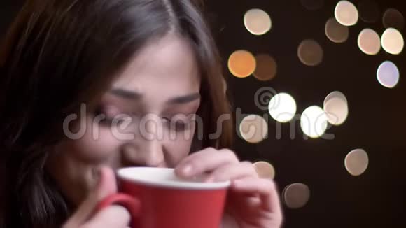 一幅年轻可爱的白种人女性的特写肖像微笑着躲在那杯温暖的茶后面带着羞怯的表情视频的预览图