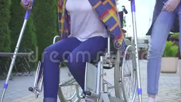 有非洲发型的非洲妇女在康复过程中在轮椅上残疾在帮助下学会走路视频的预览图