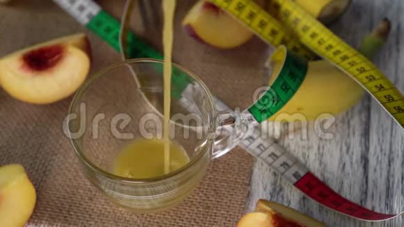 桃汁倒入玻璃杯中桌子上有桃子和一厘米的麻布视频的预览图