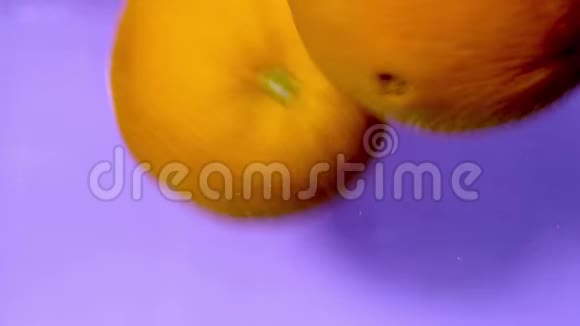 橘子在紫色背景下在水中掉落和旋转视频的预览图
