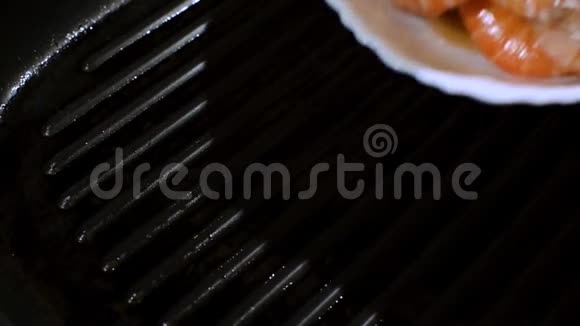虾从一个白色盘子掉进一个带有橄榄油的烤盘里视频的预览图