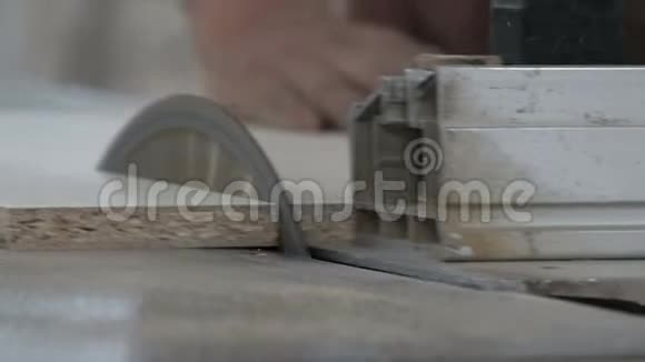 一家家具厂的一名员工在一台机器上用圆锯切割半张白色纸板特写视频的预览图