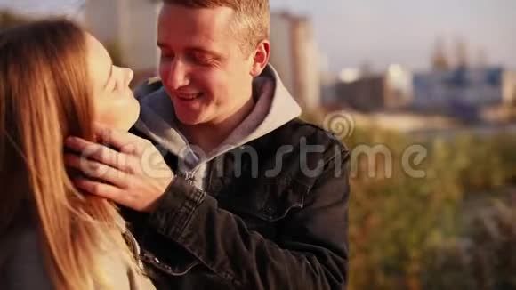 幸福的微笑夫妇站在城市中互相抚摸和亲吻视频的预览图