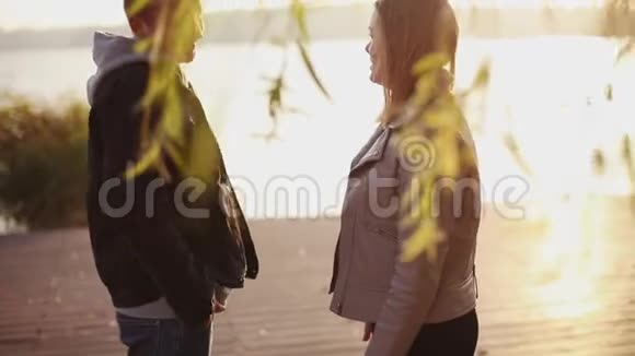 可爱的一对夫妇带着太阳眨眼的效果走到湖边视频的预览图