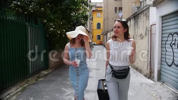 两个年轻的女人走在街上笑着其中一个提着一个手提箱视频的预览图