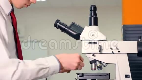 少年在学校实验室学习生物学透过显微镜看视频的预览图