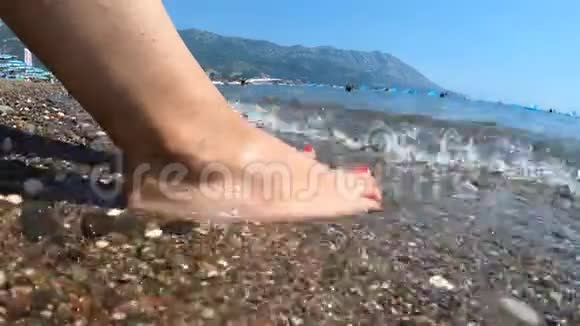 大海在海边洗了一个女孩的脚卵石海滩放松和销售复制空间时间推移视频的预览图