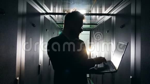 带有IT专家操作笔记本电脑的黑暗服务器单元信息技术工程师在服务器机房工作视频的预览图