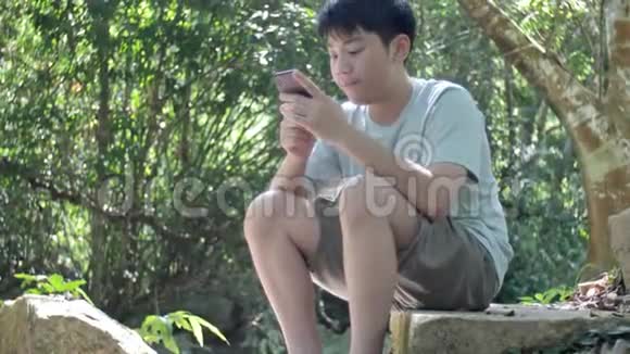 一个亚洲男性青少年在度假时会打手机视频的预览图