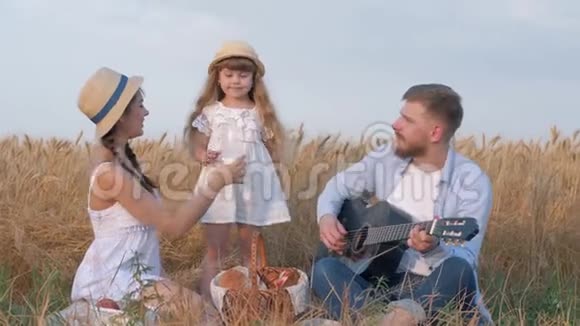 一家人在乡下野餐小女孩在和她年轻的妈妈和快乐的爸爸外出时喝着瓶子里的牛奶视频的预览图