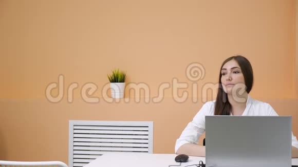 布鲁内特坐在棕色的桌子上年轻的女人来说话视频的预览图