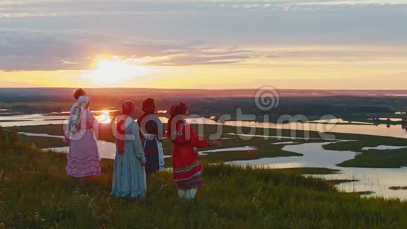 穿着俄罗斯传统服装的年轻人站在田野上欣赏日落河畔的景色很少有人看到视频的预览图