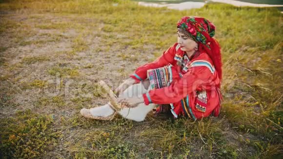 一个穿着俄罗斯民族服装穿着皮鞋的女人坐在田野上视频的预览图