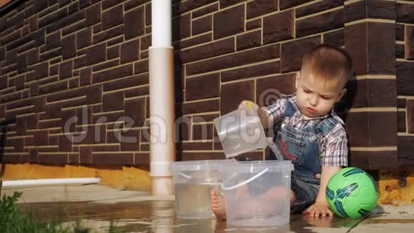 一个短发男孩从塑料桶里倒水视频的预览图