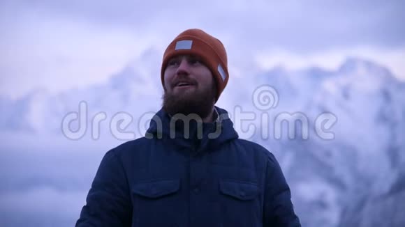 一个年轻的胡须男旅行者在暮色中在山上的肖像站着思考微笑着推理视频的预览图