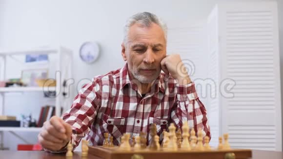 年长的男性独自下棋寻找相机准备比赛视频的预览图