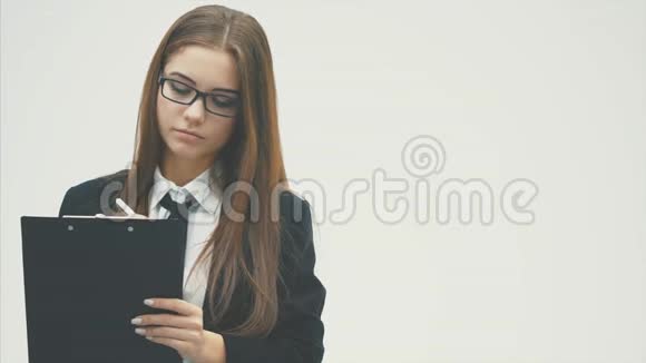 一个穿着文件夹和友好微笑的商务女孩站在白色的背景上视频的预览图