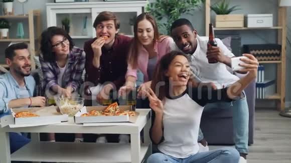 快乐的年轻人在聚会上用智能手机自拍披萨和饮料视频的预览图