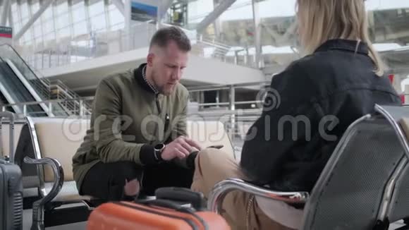 两位旅客坐在大厅里等候飞机或火车一男一女视频的预览图