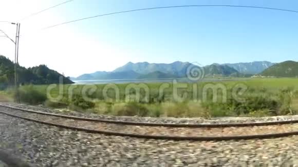 从公共汽车窗口可以看到黑山美丽的风景山脉和铁路平行视频的预览图