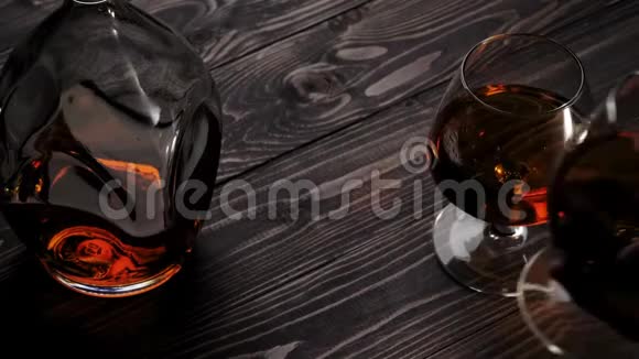 豪华白兰地手把两个玻璃杯中的一个从左边放在木桌上白兰地白兰地嗅探器狂欢慢动作视频的预览图