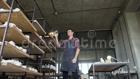 男陶工在工作日看陶器里的手工花瓶视频的预览图