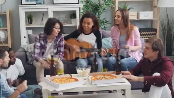 在现代公寓的聚会上女孩和男人都在弹吉他视频的预览图
