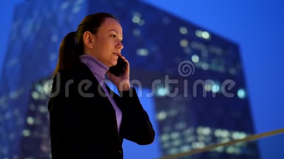 女商人用手机对着市中心的摩天大楼说话视频的预览图