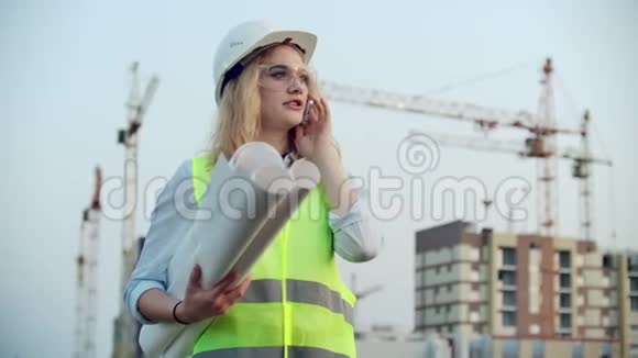 电话对话一名戴头盔的妇女在建筑背景下与主任讨论视频的预览图