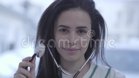 美丽微笑的年轻医生近照一个长着黑发的可爱女人拿着相机看着视频的预览图