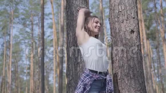 美丽的年轻女子伸展身体在松林里做运动健康的生活方式与自然的统一短视频的预览图