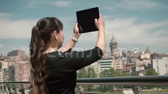 女游客站在城市的一个美丽的区域附近在平板电脑蓝天上拍照视频的预览图