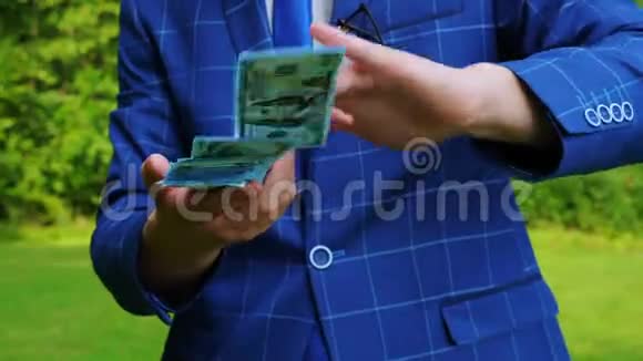 一个年轻的商人穿着一套蓝色的格子西装用手扔钱视频的预览图