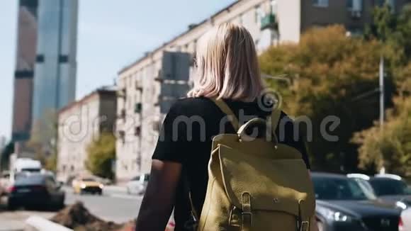 这个女孩在阳光明媚的天气里穿过城市背上背包视频的预览图