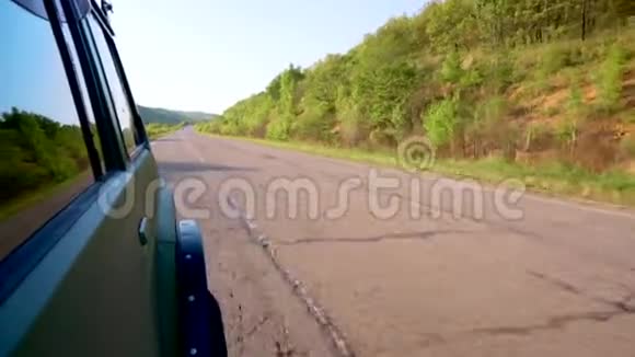 一辆旅游汽车在森林和田野之间的沥青路上行驶视频的预览图