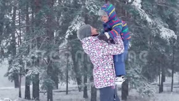 一位快乐的母亲把儿子高高地举起来在一个下雪的冬天和他接吻视频的预览图