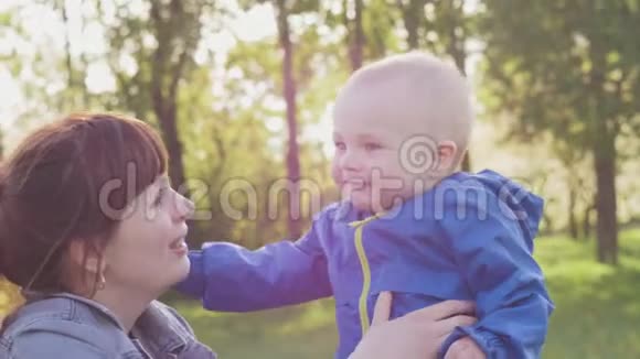 妈妈带着一个带着一个小孩子的妈妈正在公园里散步妈妈吻了宝宝在日落时散步小孩躺在床上视频的预览图