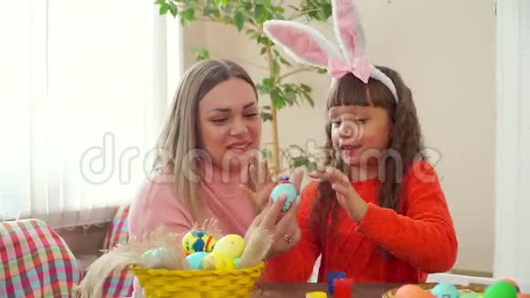 妈妈拿着一个蓝色的鸡蛋我女儿用你的手指涂满了油漆留下了痕迹她穿兔子视频的预览图
